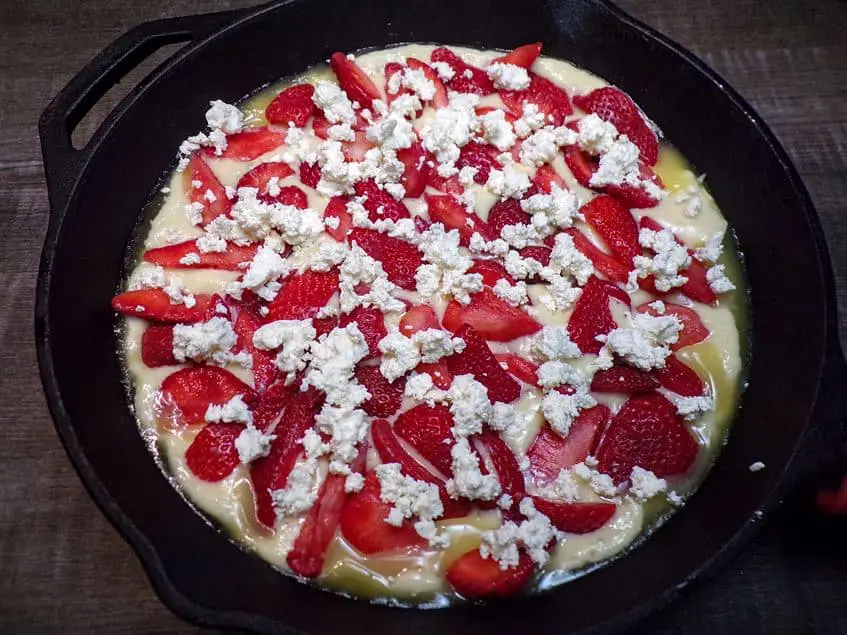 Skillet with dough strawberries-and cheese ready for oven
