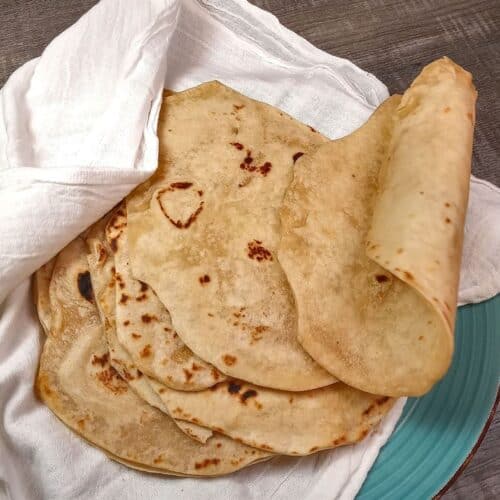 Stack of soft flour tortillas with a bakers sack cloth.