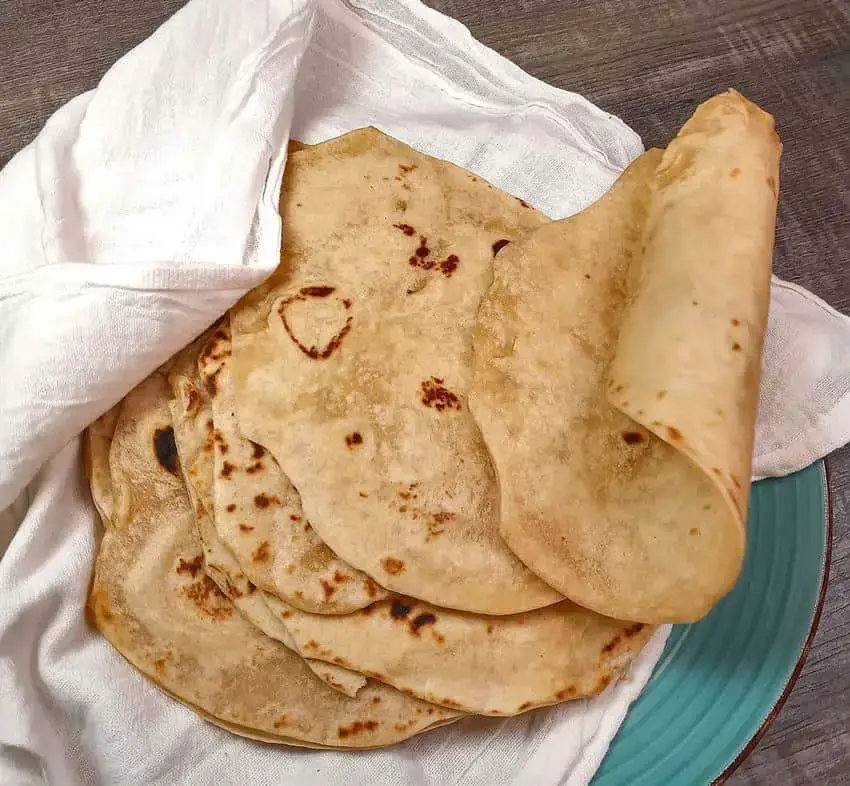 Stack of soft flour tortillas with a bakers sack cloth.