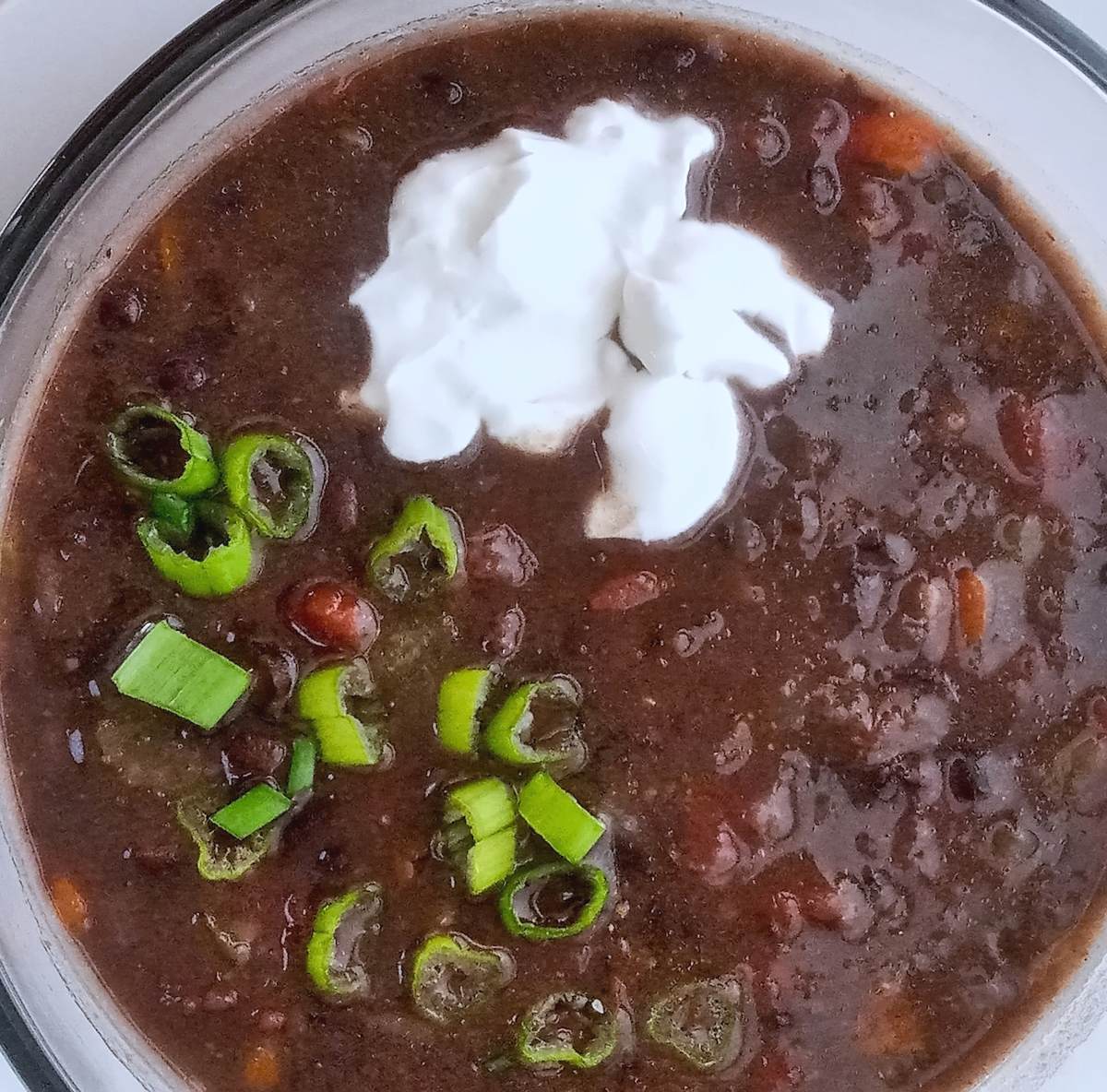 Warm bowl of low sodium black bean soup with chives and sour cream