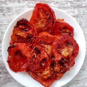 Overhead view of piled and sliced low sodium roasted tomatoes "sun-dried" on white plate.