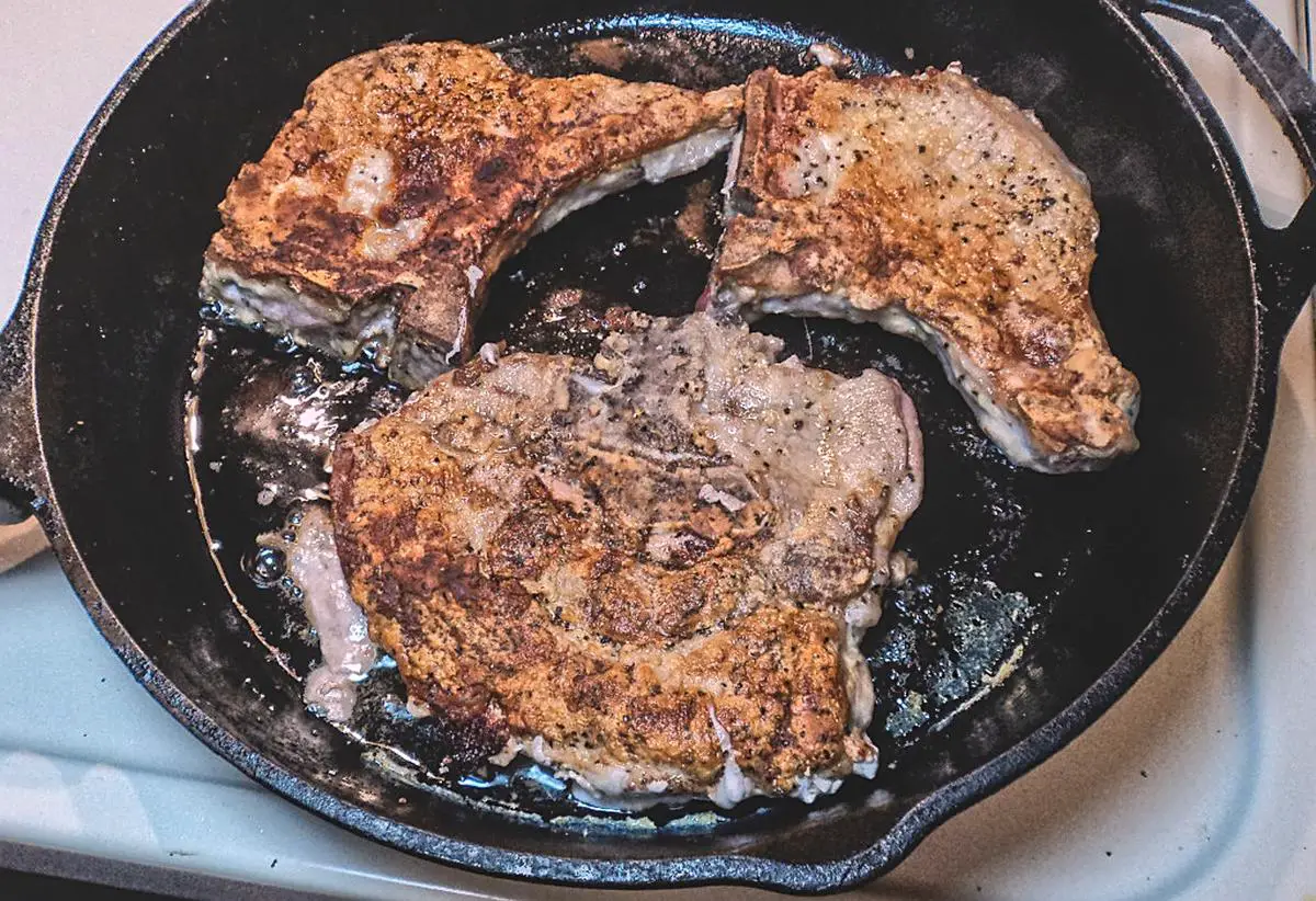 Pork chops searing in skillet