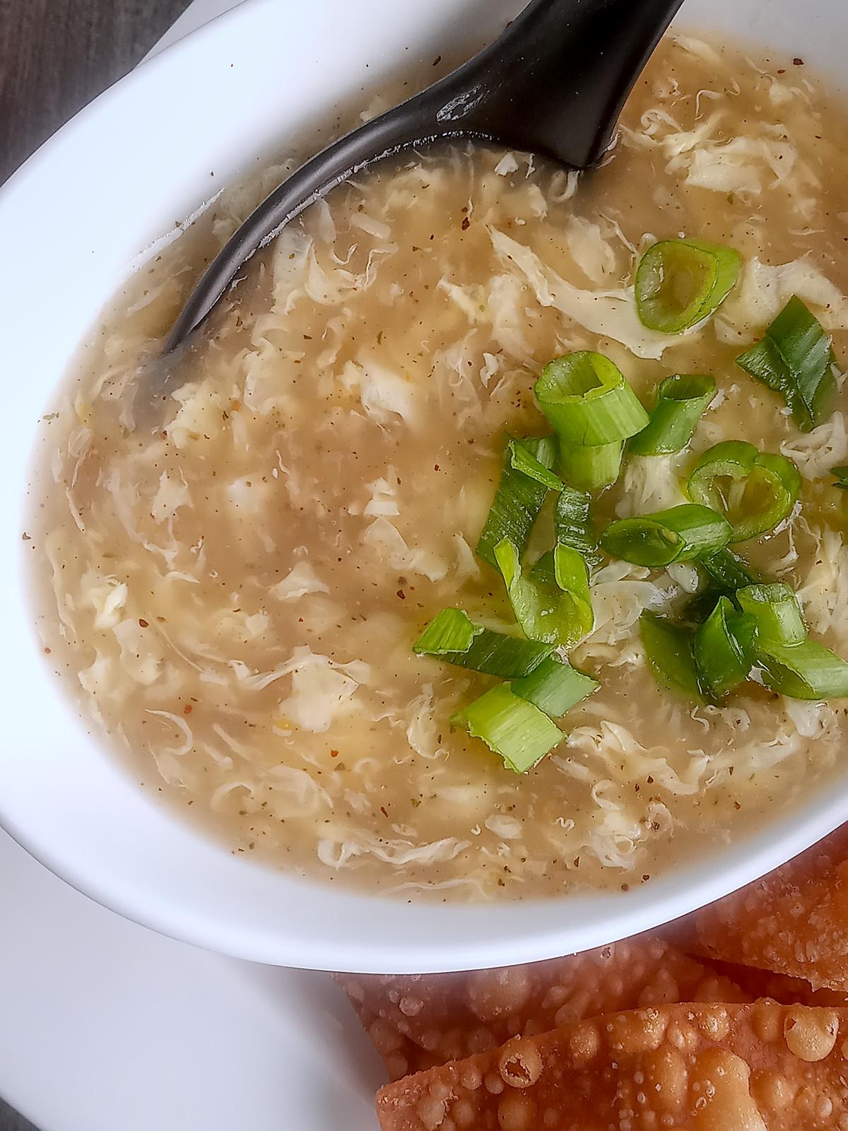 Egg drop soup with scallions garnish.