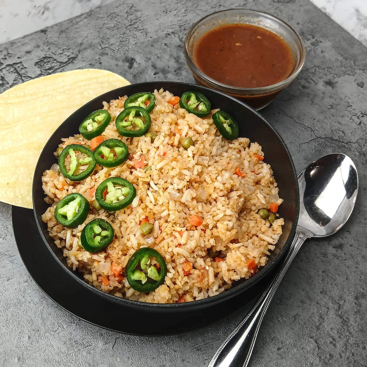 Low sodium Mexican rice in black bowl with enchilada sauce