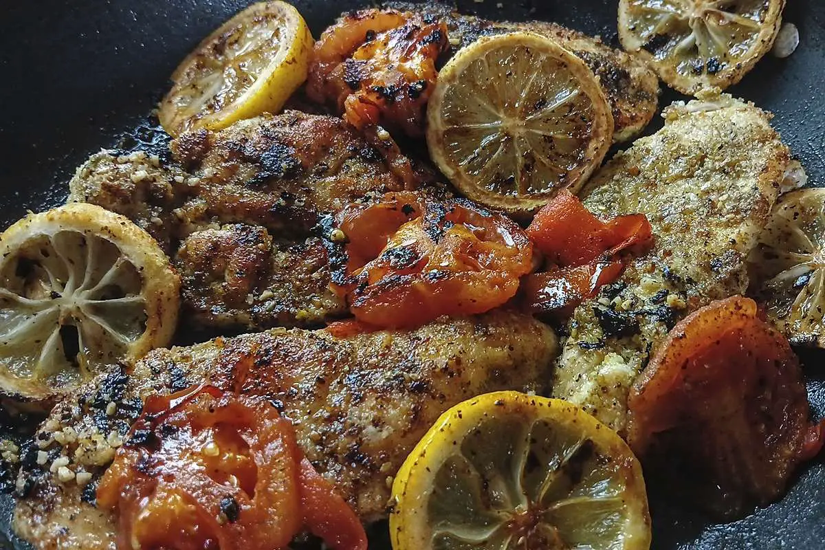 Low Sodium Lemon pepper chicken close up of chicken lemons and tomatoes presentation