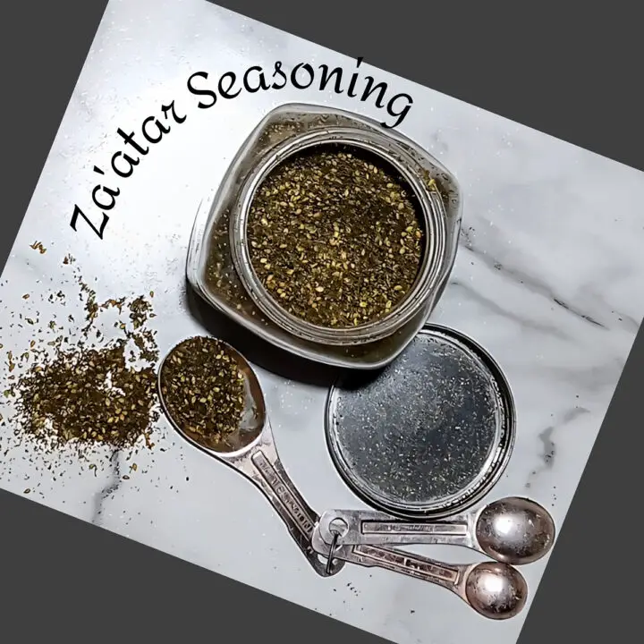 Top view of za'atar-seasoning in a jar, measuring spoons and scattered on the counter.