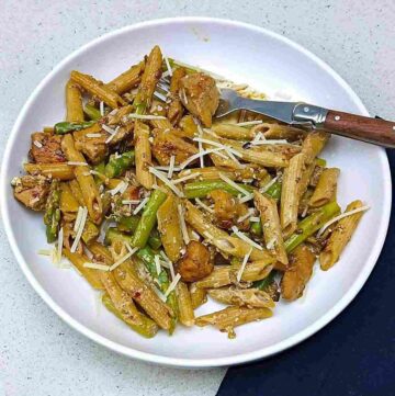 Low sodium chicken pasta with asparagus on a white plate the sprinkling of shredded parmesan.