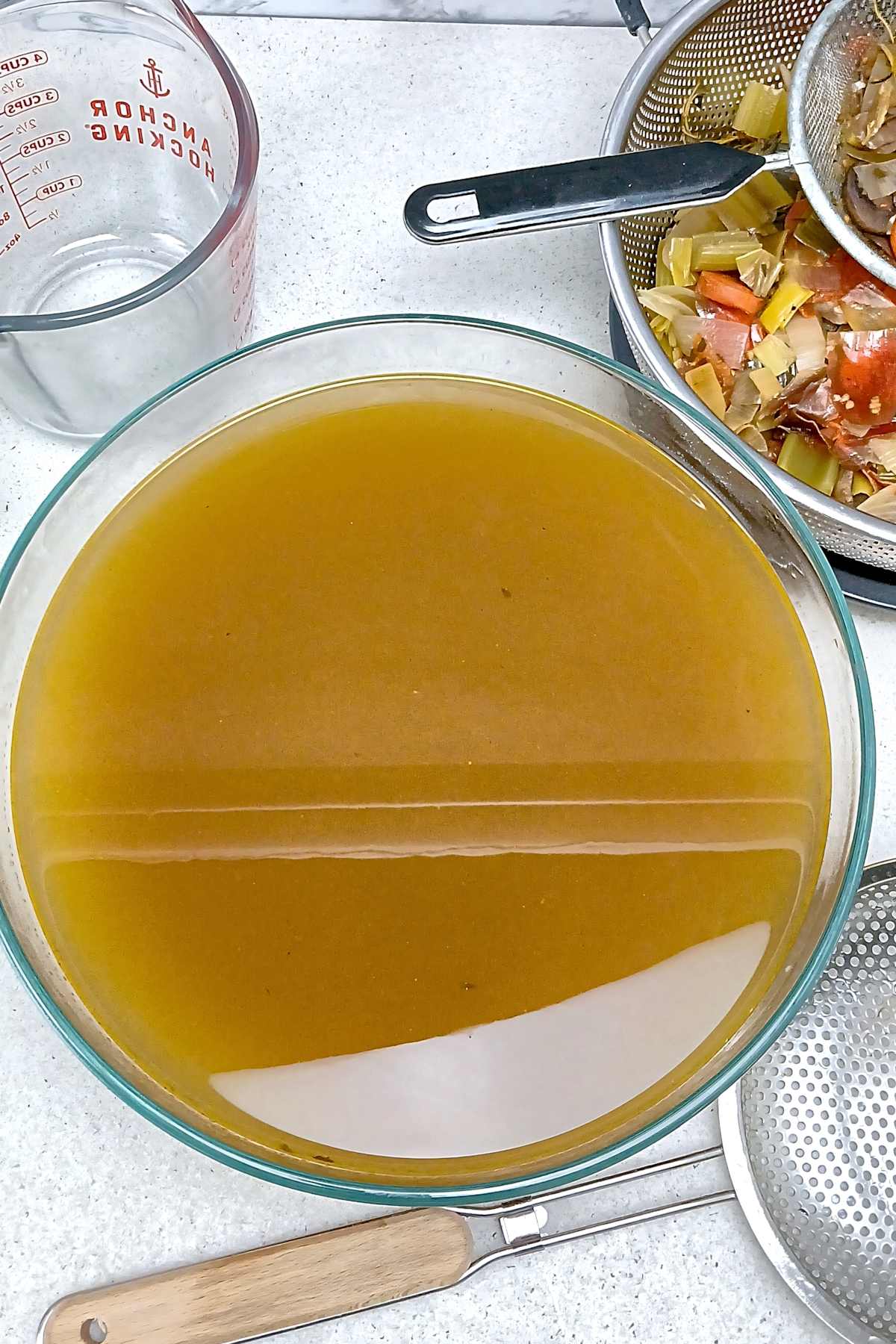 Low sodium vegetable broth stock in large glass mixing bowl overhead.