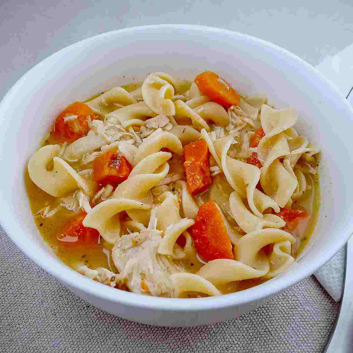 Bowl of shredded chicken noodle soup.