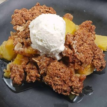 Low sodium pineapple crisp, golden strudel and ice cream on baked pineapple black dish. F1