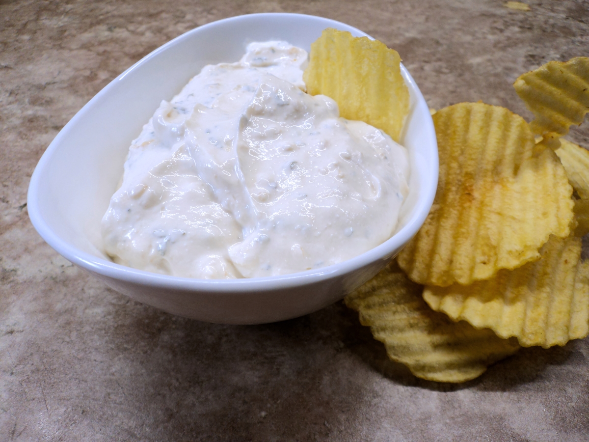 Low sodium french onion dip in a white bowl with a chips in it.