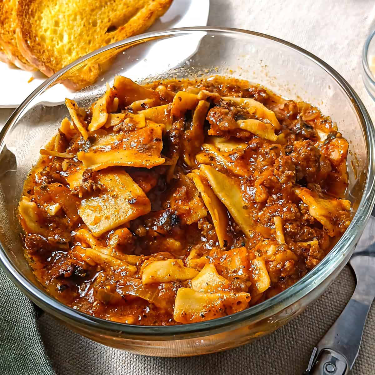 Low sodium lasagna soup in a bowl with low sodium garlic bread in the background.