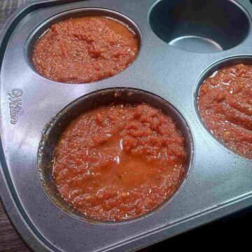 Pizza sauce portioned into jumbo muffin tin for freezing.